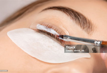 Wimpern liegen auf einem Silikonpad und werden mit einem Pinsel behandelt
