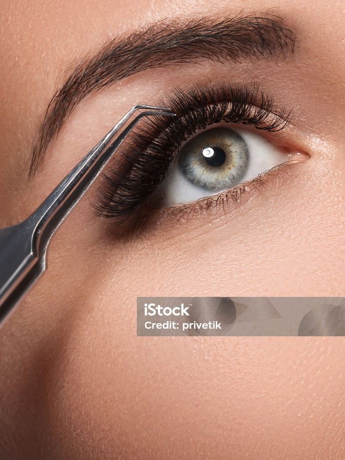 Nahaufnahme eines Auges mit langen, geschwungenen Wimpern und einer Pinzette